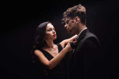 Kızıl dudaklı esmer kadın, adama bakıyor ve siyah saçlarını çekiyor.