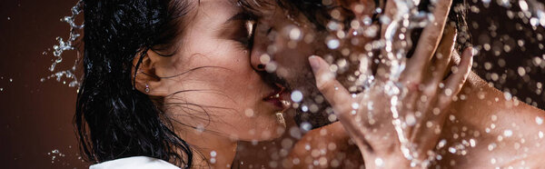 young couple kissing with closed eyes near water splashes on dark background, banner