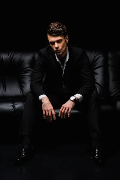 Seriózní Muž Formálním Oblečení Sedí Pohovce Černém Pozadí — Stock fotografie