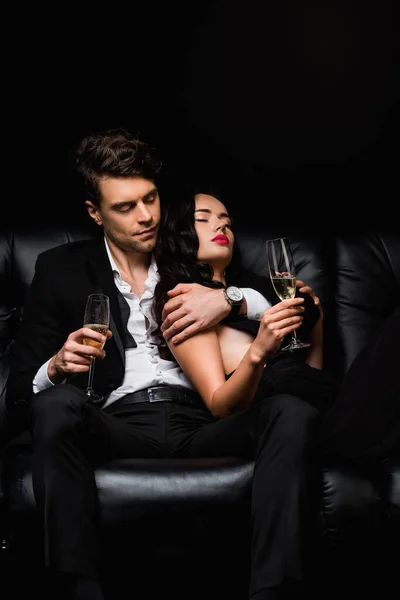 Siyah Kanepede Dinlenirken Ellerinde Şampanya Bardakları Olan Çift — Stok fotoğraf