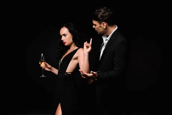 ブルネット女性でドレス保持ガラスのシャンパンとポインティングとともに指近くDisplied男でスーツ絶縁上黒 — ストック写真