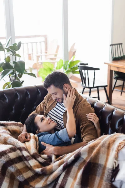 Feliz Joven Pareja Abrazando Mientras Descansa Sofá Cuero Bajo Acogedora — Foto de Stock