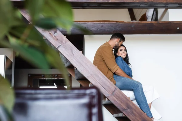 Young Couple Embracing While Sitting Wooden Stairs Home Blurred Foreground — Stock Photo, Image