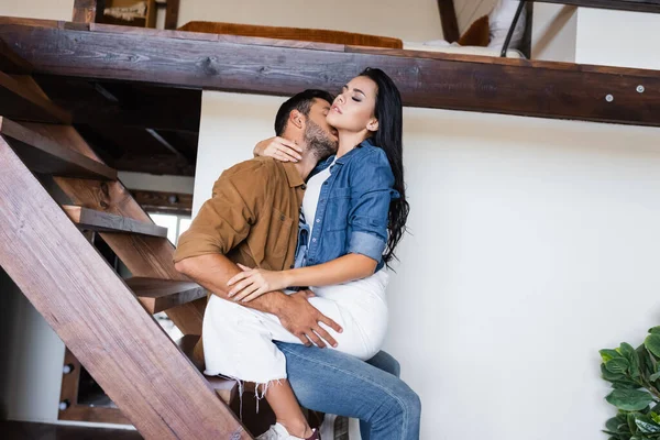 一对年轻夫妇穿着时髦的休闲装 拥抱在家里的木制楼梯上 — 图库照片