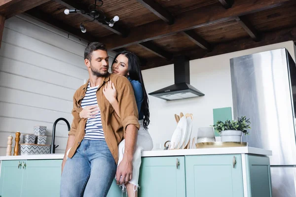 Happy Young Woman Sitting Kitchen Counter Embracing Boyfriend — Stock Photo, Image