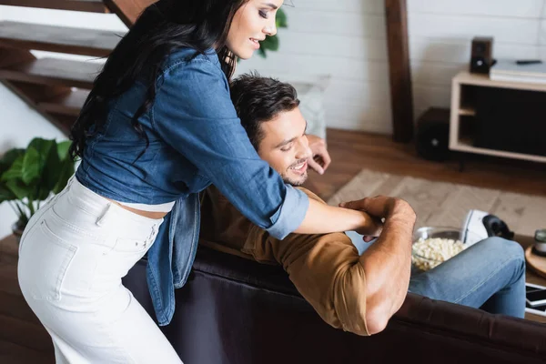 Sensual Mulher Abraçando Jovem Namorado Sentado Sofá Casa — Fotografia de Stock