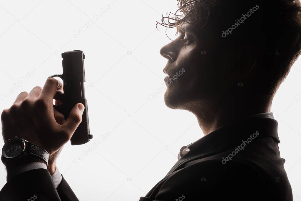 side view of armed man in formal wear holding gun isolated on white