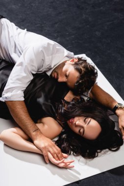 Gömlekli bir adamın siyah-beyaz zeminde uzanan saten elbiseli bir kadını baştan çıkardığını gördüm.