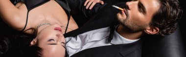 Gözü kapalı, seksi bir kadının yanında sigara içen zarif bir adam manzarası.