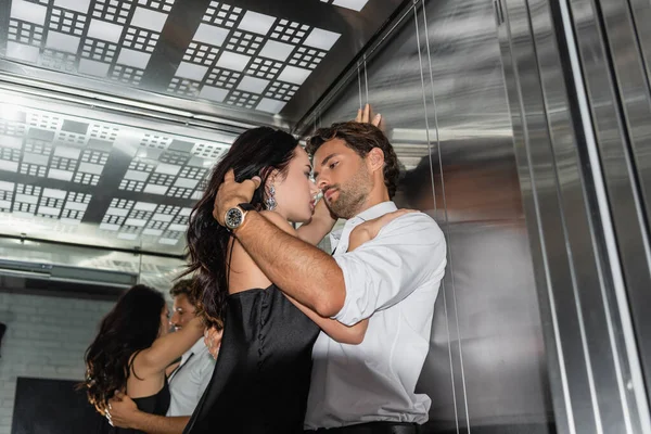 雅致的年轻夫妇在电梯里面对面拥抱 — 图库照片