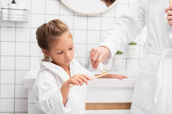 Madre Spremitura Dentifricio Sulla Spazzola Vicino Figlia Bagno — Foto Stock