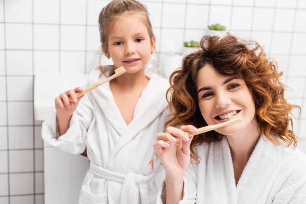 Smiling Woman Brushing Teeth Daughter Blurred Background Bathroom — ストック写真