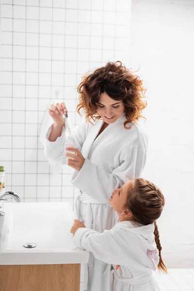 Child Embracing Mother Cosmetic Serum Bathroom — Stock Photo, Image