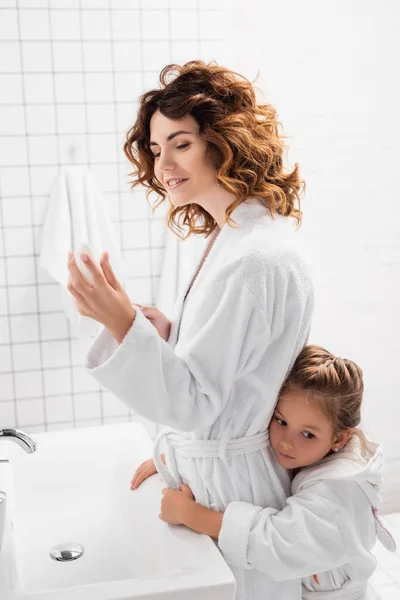 バスルームで子供の近くに消臭剤を保持笑顔女性 — ストック写真