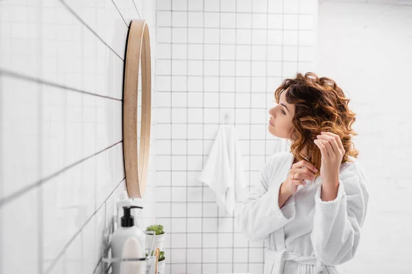 Mujer Rizada Albornoz Ajustando Cabello Cerca Del Espejo Baño — Foto de Stock