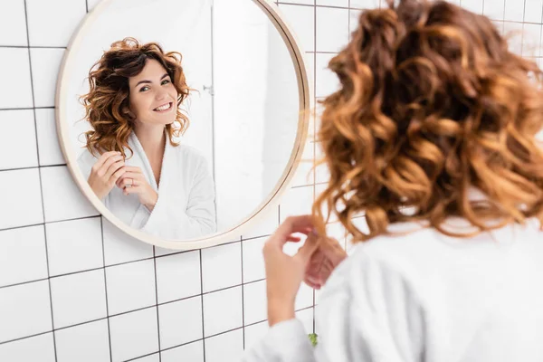 Mulher Alegre Roupão Banho Ajustando Cabelo Olhando Para Espelho Primeiro — Fotografia de Stock