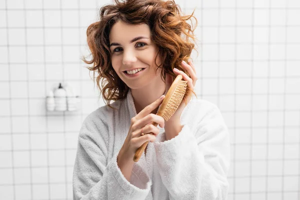 Улыбающаяся Женщина Смотрит Камеру Расчесывая Волосы — стоковое фото