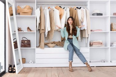 Worried woman pointing with hands in wardrobe  clipart