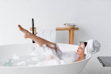 Kafasında havluyla banyo yapan mutlu kadın. 