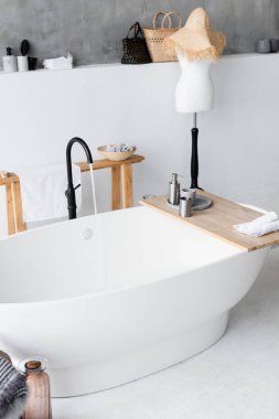 Toiletries on wooden tray on bathtub at home  clipart