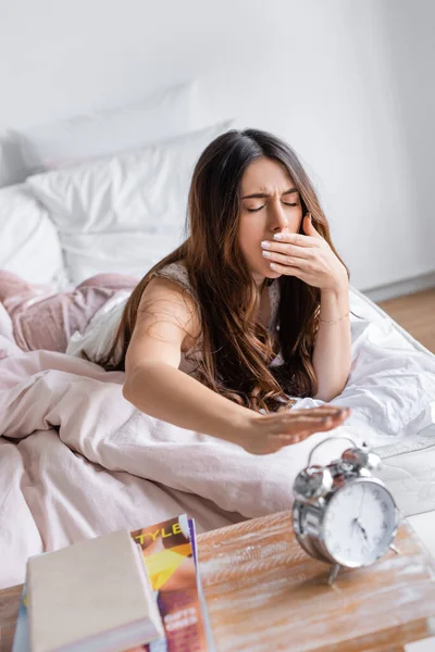 Mujer Bostezando Tirando Mano Reloj Despertador Primer Plano Borroso Dormitorio — Foto de Stock