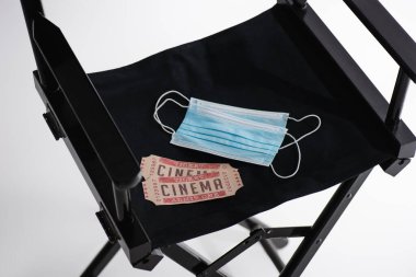 Yüksek açılı güvenlik maskeleri ve sinema biletleri beyaz sinema konsepti üzerine film yapımcısı koltuğu üzerinde