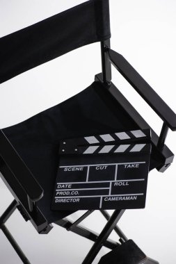 high angle view of clapperboard on director chair on white, cinema concept clipart