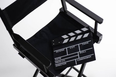 high angle view of clapperboard on director chair on white, cinema concept clipart