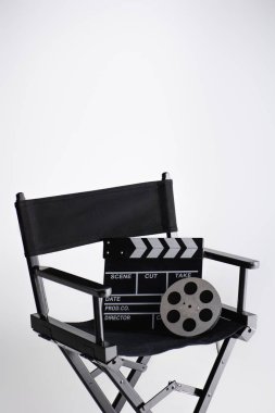 Kopyalama tahtası ve film makarası, yönetmen koltuğunun üzerinde, kopyalama alanı ve sinema konseptiyle birlikte.