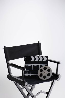 clapperboard and film reel on director chair on white with copy space, cinema concept clipart