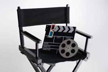 clapperboard, 3d glasses and film coil on filmmaker chair on white, cinema concept clipart