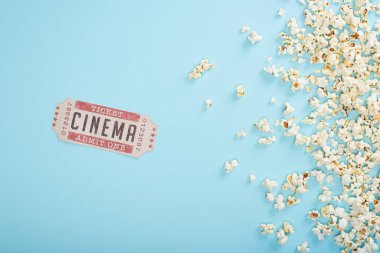 Sinema biletinin üst görüntüsü mavi üzerine dağınık patlamış mısır.
