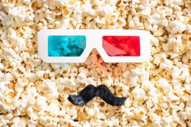 3D gözlükler ve dağınık patlamış mısır üzerindeki yapay bıyık, sinema konsepti.