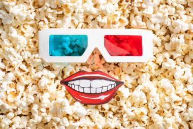 3D gözlük ve kağıdın üst görüntüsü gevrek patlamış mısırla gülen ağız, sinema konsepti.