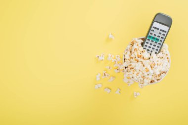 TV uzaktan kumandasının üst görüntüsü kova dolusu patlamış mısır, sinema konsepti.