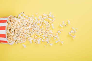 Kağıt kovanın üst görüntüsü ve dağınık patlamış mısır sarı üzerine, sinema konsepti.