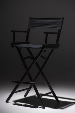 modern, black filmmaker chair on dark grey background, cinema concept clipart