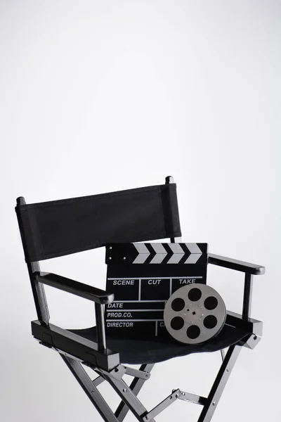 stock image clapperboard and film reel on director chair on white with copy space, cinema concept