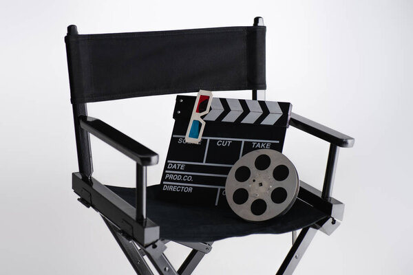 clapperboard, 3d glasses and film coil on filmmaker chair on white, cinema concept