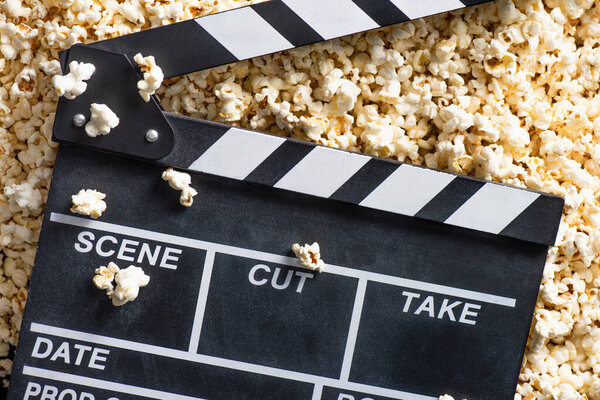 top view of clapperboard on salty popcorn, cinema concept