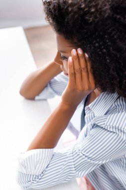 Afro-Amerikalı kadın masada baş ağrısı çekiyor. 