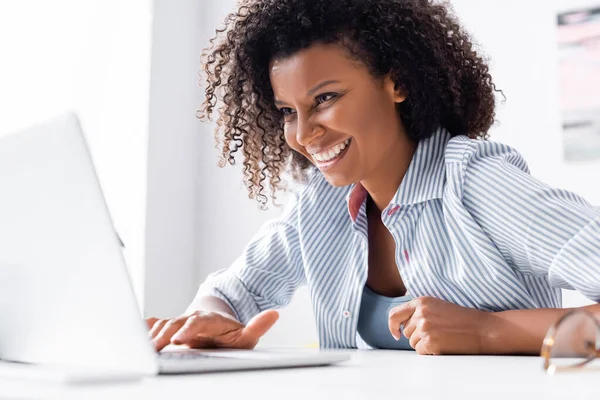 African American Freelancer Smiling While Using Laptop Blurred Foreground — Stock Photo, Image