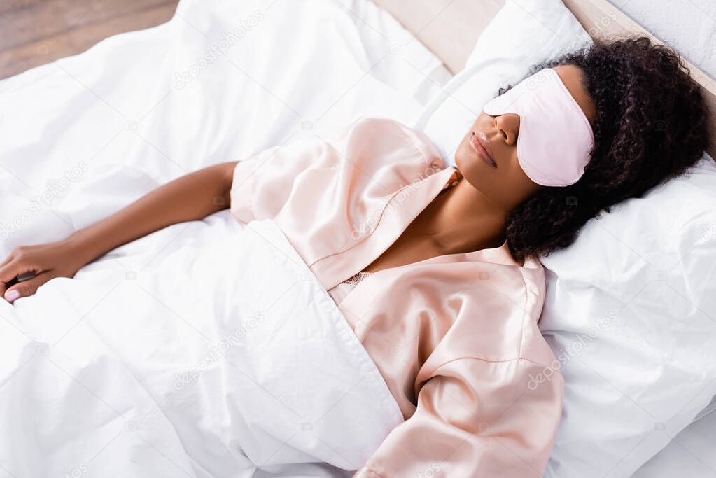 African american woman in mask sleeping on bed 