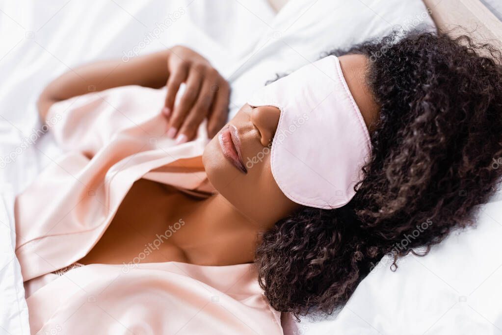 Curly african american woman sleeping in mask at home 