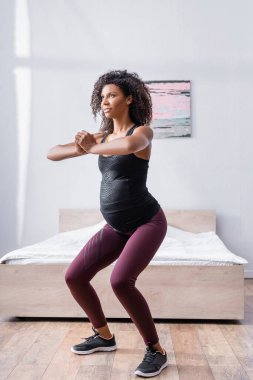 Hamile Afrikalı Amerikalı kadın yatak odasında çalışıyor. 