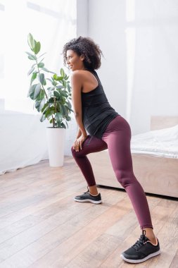 Hamile Afro-Amerikan kadının yatak odasında antrenman yaparken gülümsemesi. 