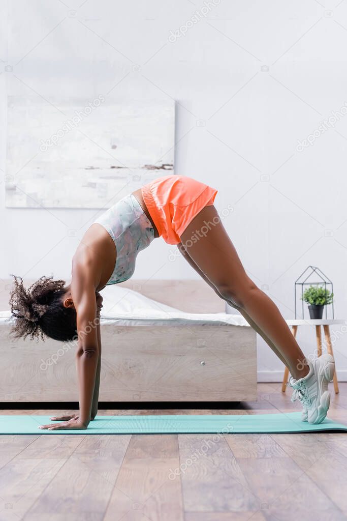 African american sportswoman exercising on fitness mat at home 