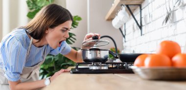 Modern mutfakta, ocağın yanında yemek pişiren üzgün genç bir kadın.