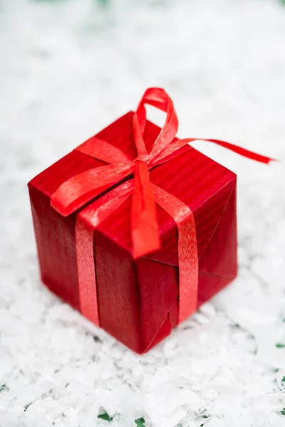 Red gift box with ribbon and bow on decorative snow surface — Stock Photo