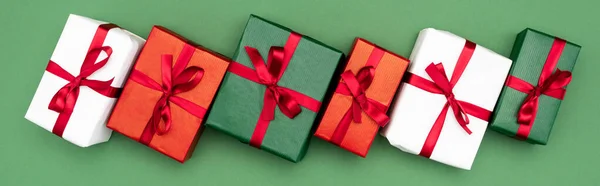 Заголовок веб-сайту різнокольорових подарункових коробок з червоними стрічками та бантами на зеленому фоні, вид зверху — стокове фото
